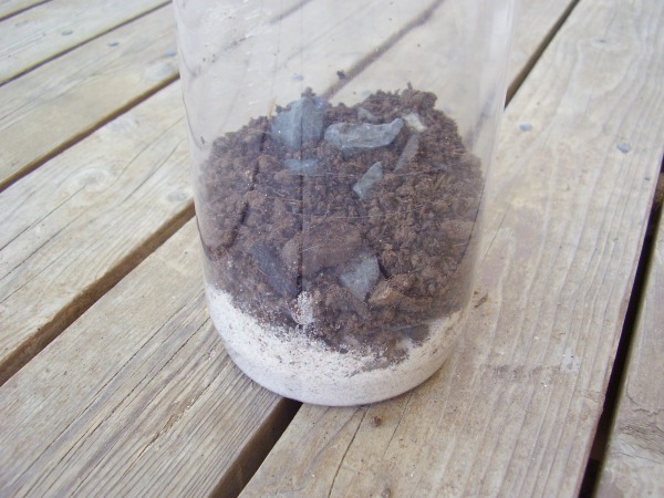 Add sand gravel and soil to a plastic jar