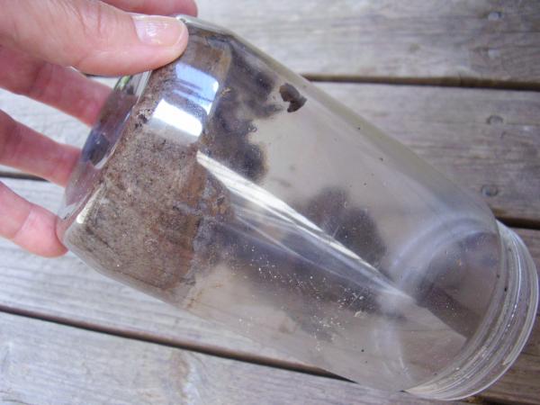 Pour water out of the jar of mixed materials in a science activity for kids