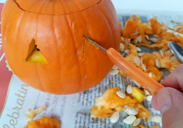 Cut eyes, nose and mouth in a pumpkin to make a jack-o-lantern 