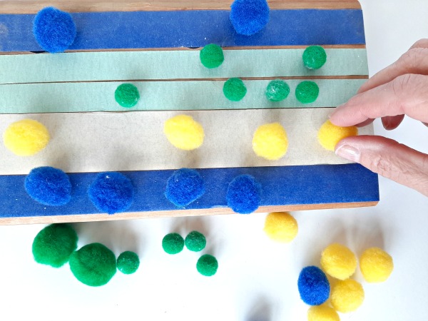 Sort pompoms by color on sticky tape