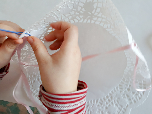Kids lacing activity with ribbon and paper doily