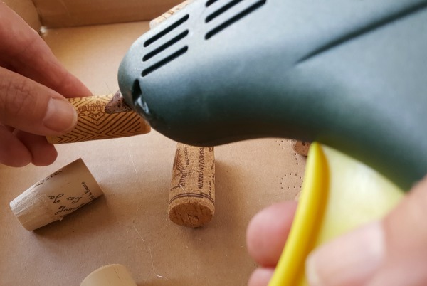 Attach corks to cardboard box with glue gun