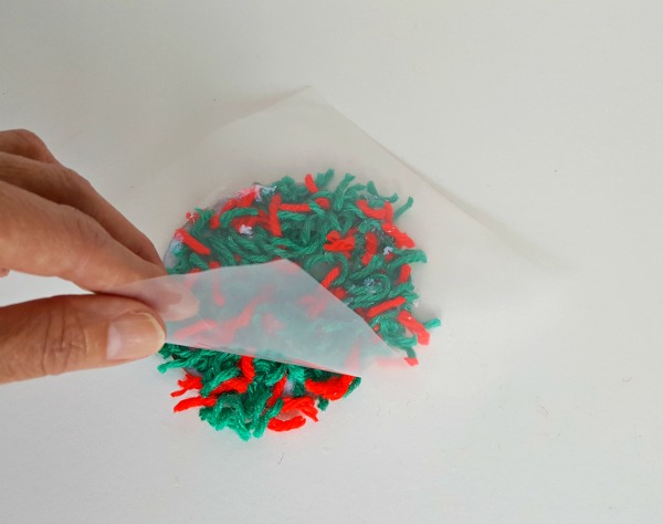 Press yarn scraps onto cardboard for kid made ornament