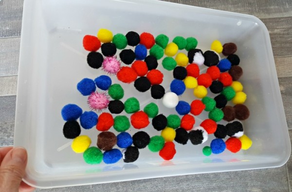 tip the container to roll the marble around with the pompoms