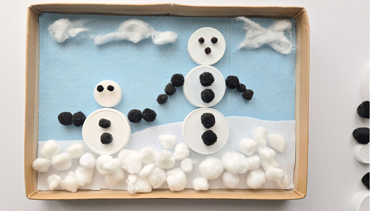 jar lids arranged on felt lined box to make a snow person