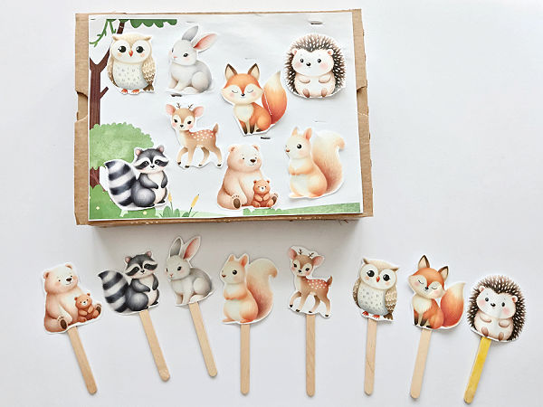 woodland printable scene taped to a box and stick puppets made with animal cutouts