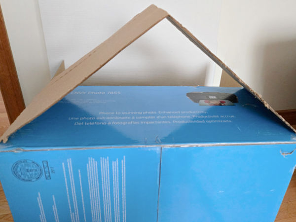 slanted cardboard roof attached to the doll house with tape