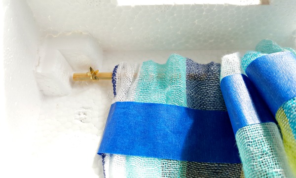 Paper fasteners hold the curtain rod in place on the inside of the puppet theater
