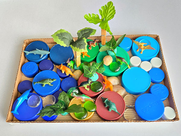 fun dinosaur play for kids with a cardboard box and jar lids